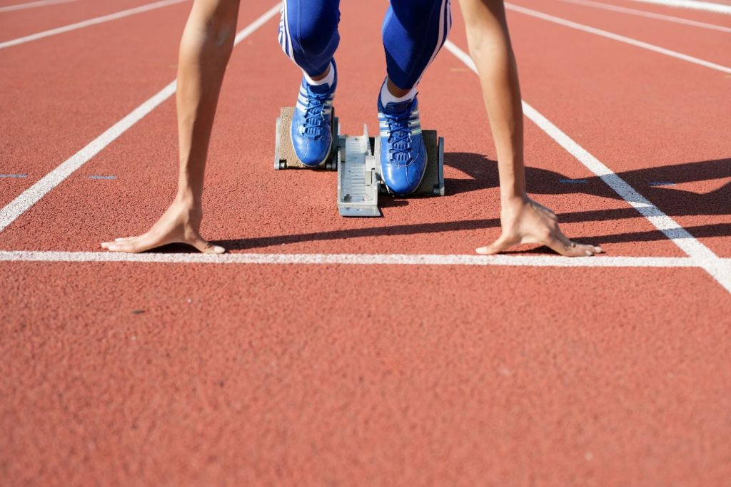 Close-up of an athlete starting a race at the track field on a sunny day.