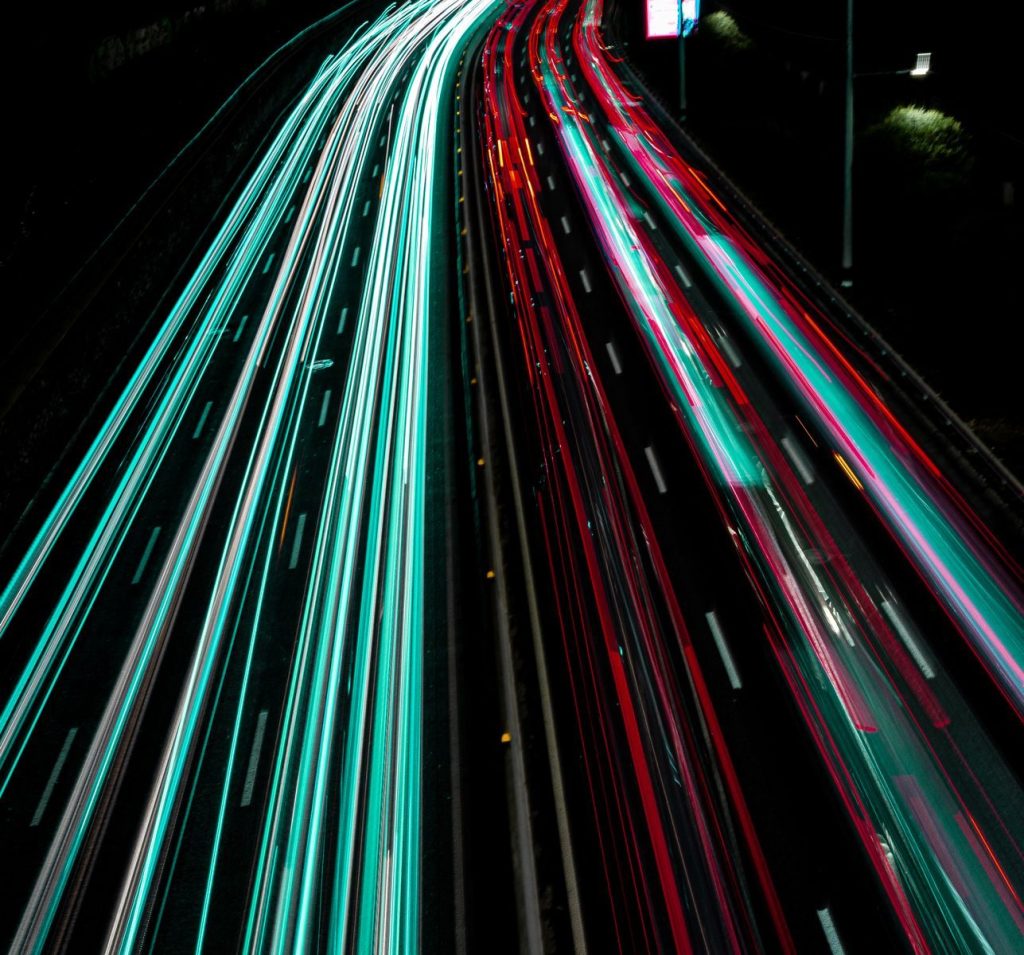 Long exposure photo capturing vibrant light trails on a highway at night.