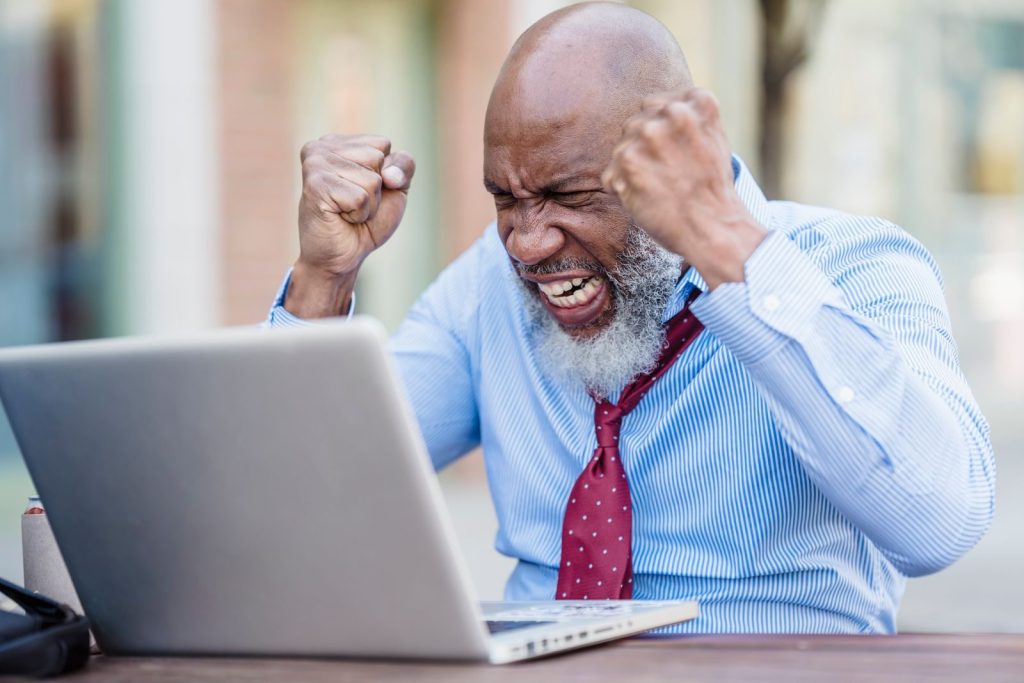 African American businessman showing frustration working on a laptop outdoors.